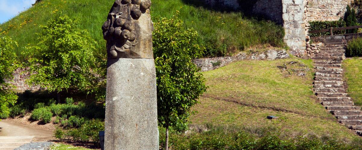 A historic stone tower with a flag, surrounded by lush greenery and a clear blue sky.