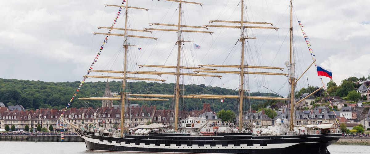 A tall ship with multiple masts sailing in a harbor.