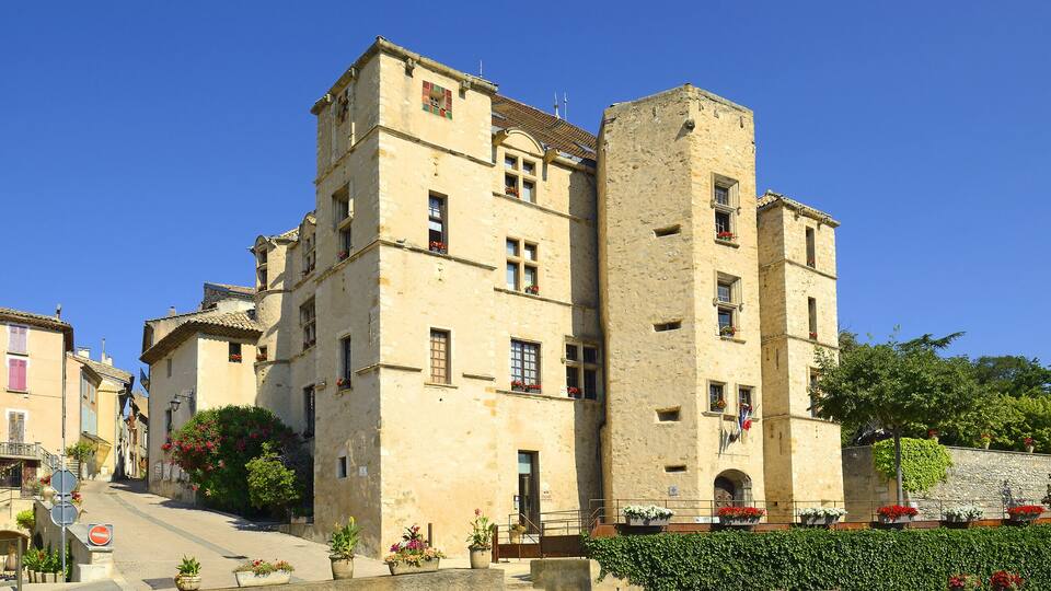 A historic building with a tower, multiple windows, and flower boxes.
