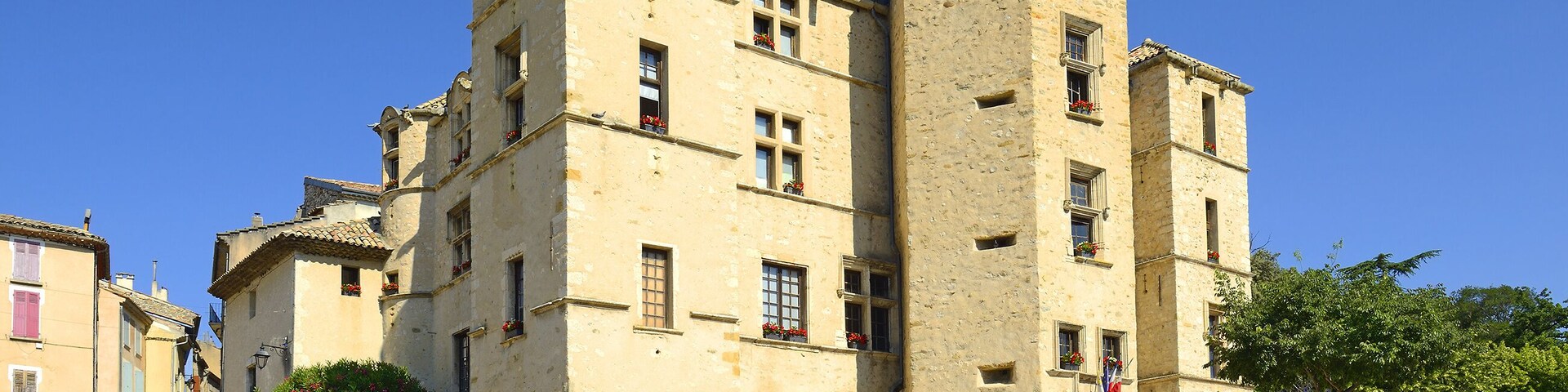 Un edificio histórico con una torre, varias ventanas y balcones con flores.