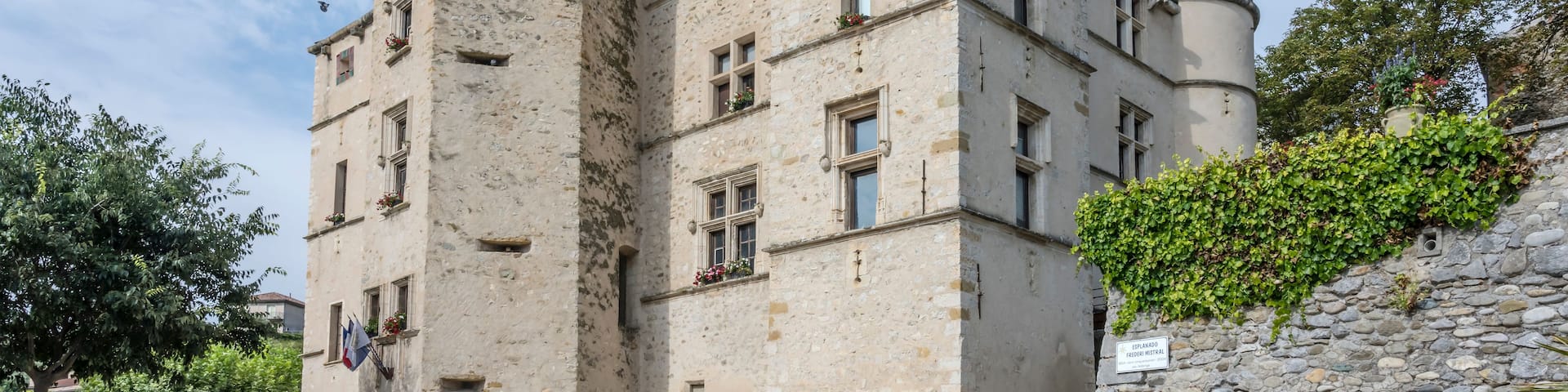 A historic stone building with multiple windows and a tower.
