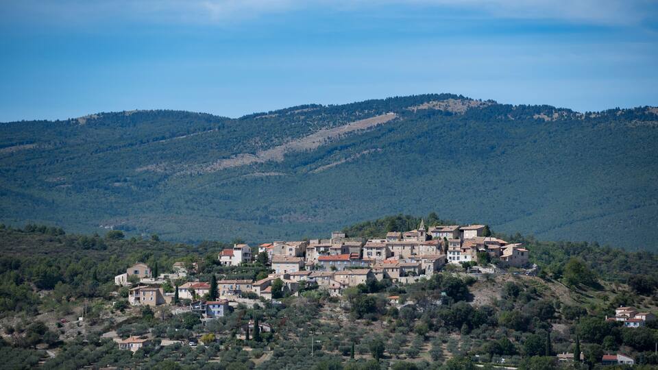 A hillside village with traditional architecture nestled among green hills.