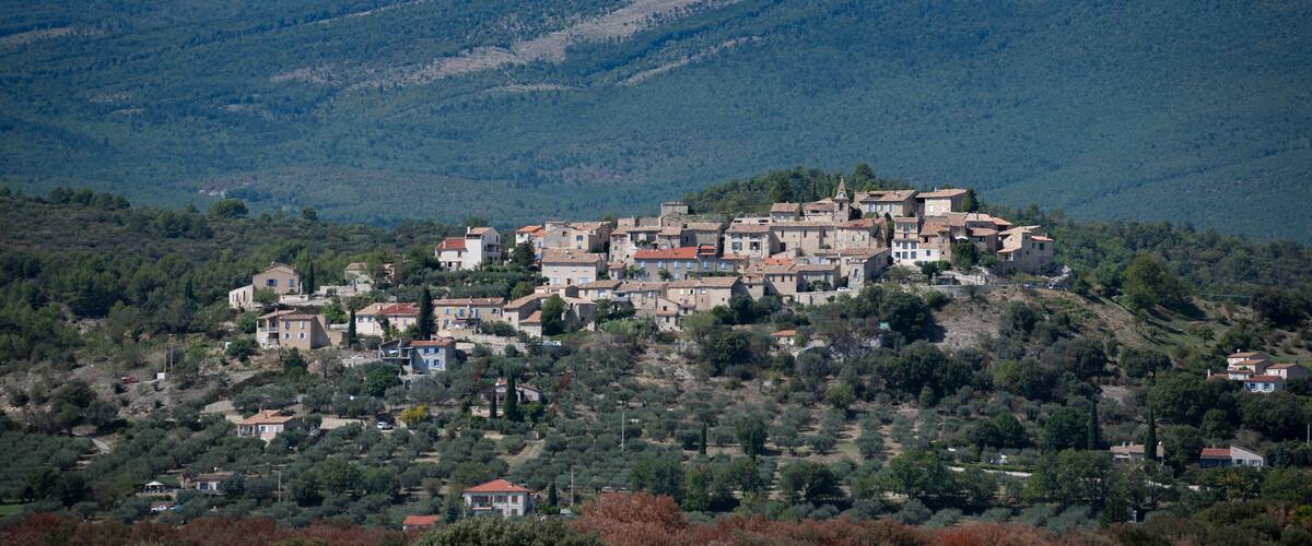 A hillside village with traditional architecture nestled among green hills.