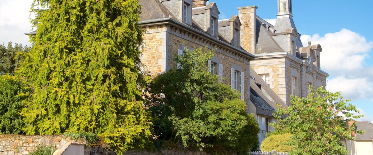 A historic building with stone walls, a large tree, and a clear blue sky.
