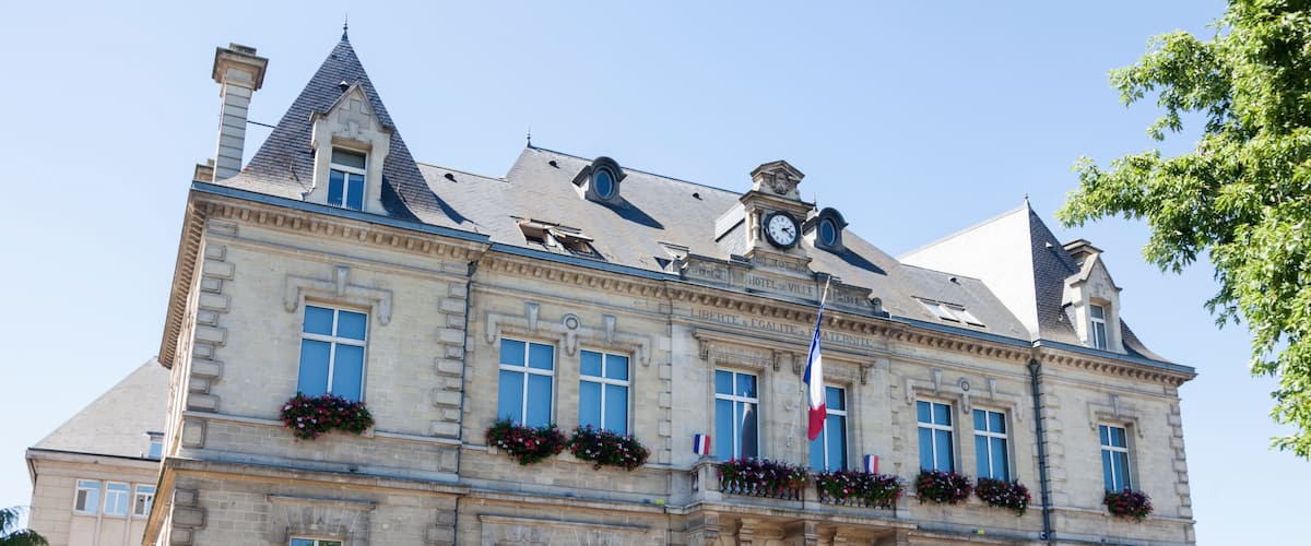 A historic building with a clock tower, large windows, and flower boxes.