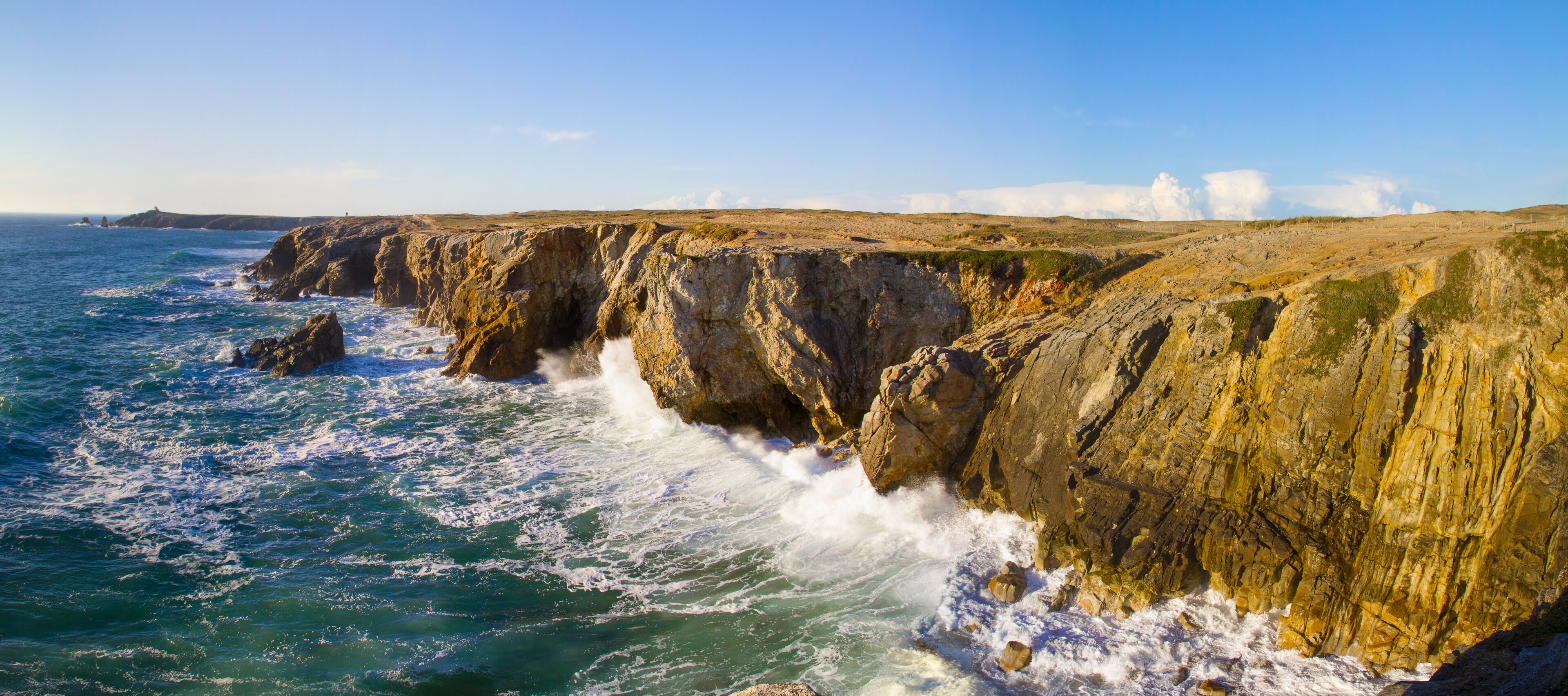 A coastal cliff with waves crashing against it.