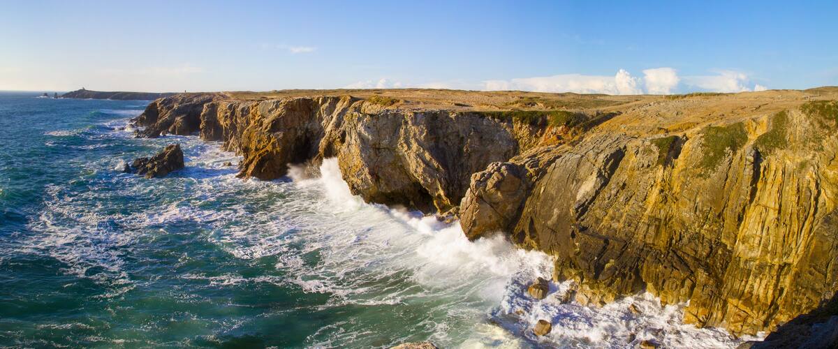 A coastal cliff with waves crashing against it.