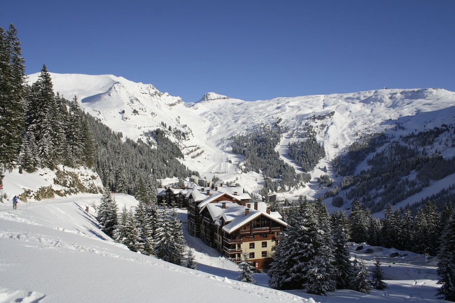 Une montagne enneigée, avec un chalet et des pistes de ski.