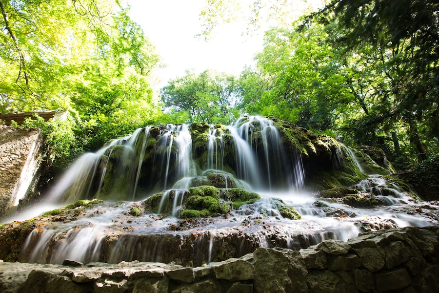 A multi-tiered waterfall surrounded by lush green foliage.