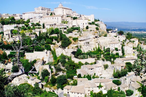 Une ville historique construite sur une colline, avec des bâtiments en pierre et une végétation luxuriante.