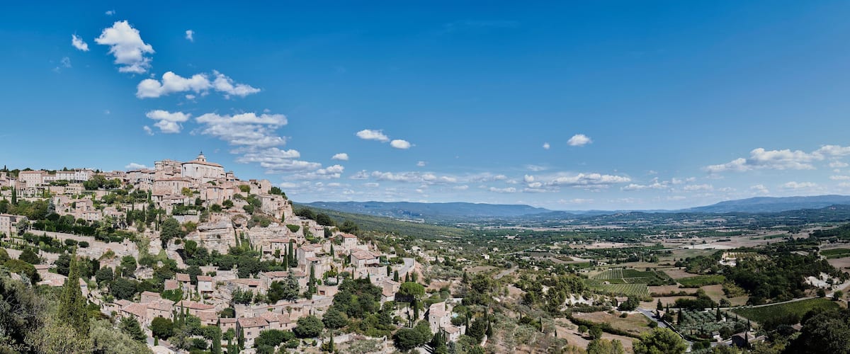A mountainous village with historic buildings and vineyards.