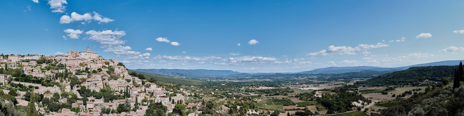 A mountainous village with historic buildings and vineyards.