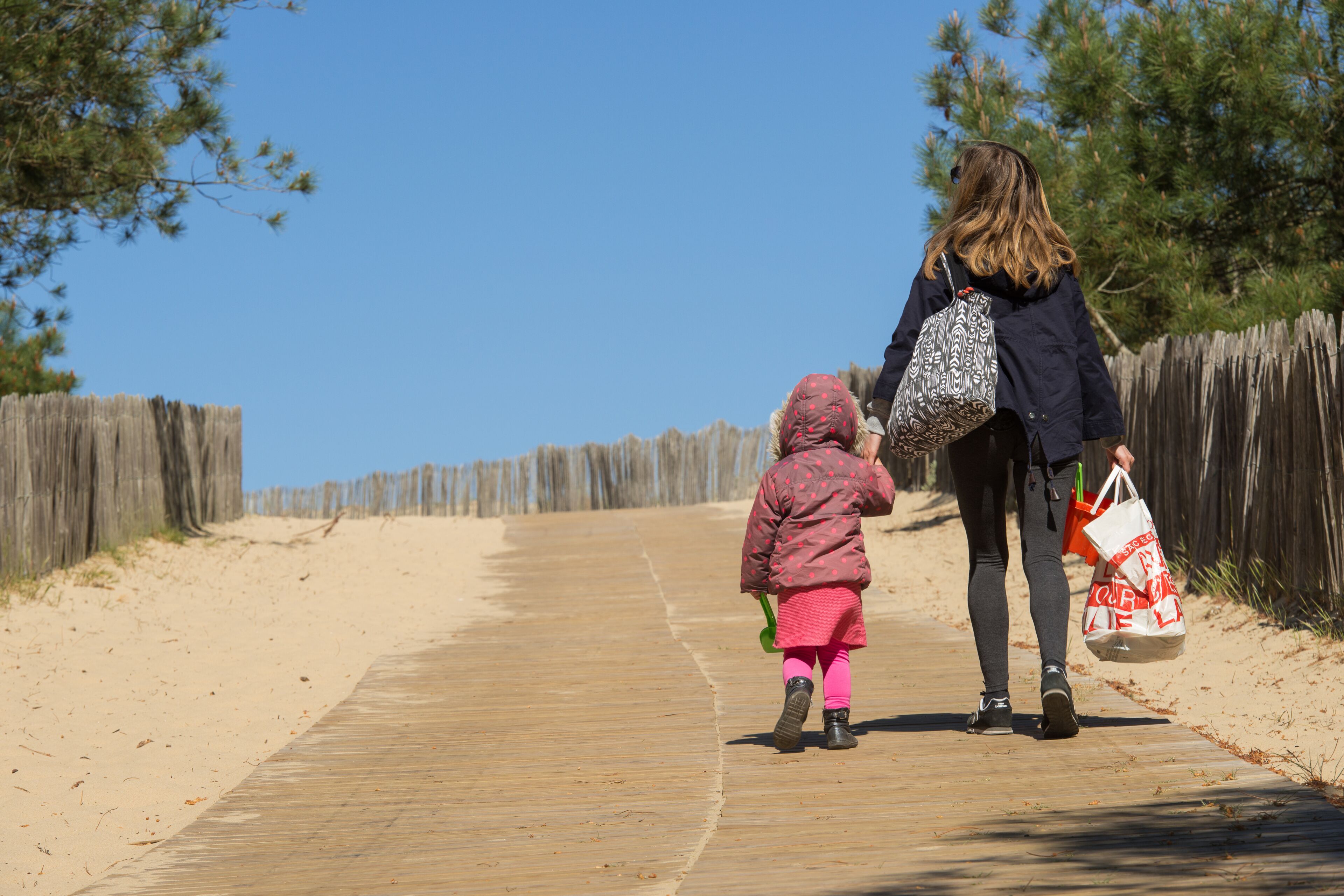 A wooden boardwalk, sandy beach, and a wooden fence.