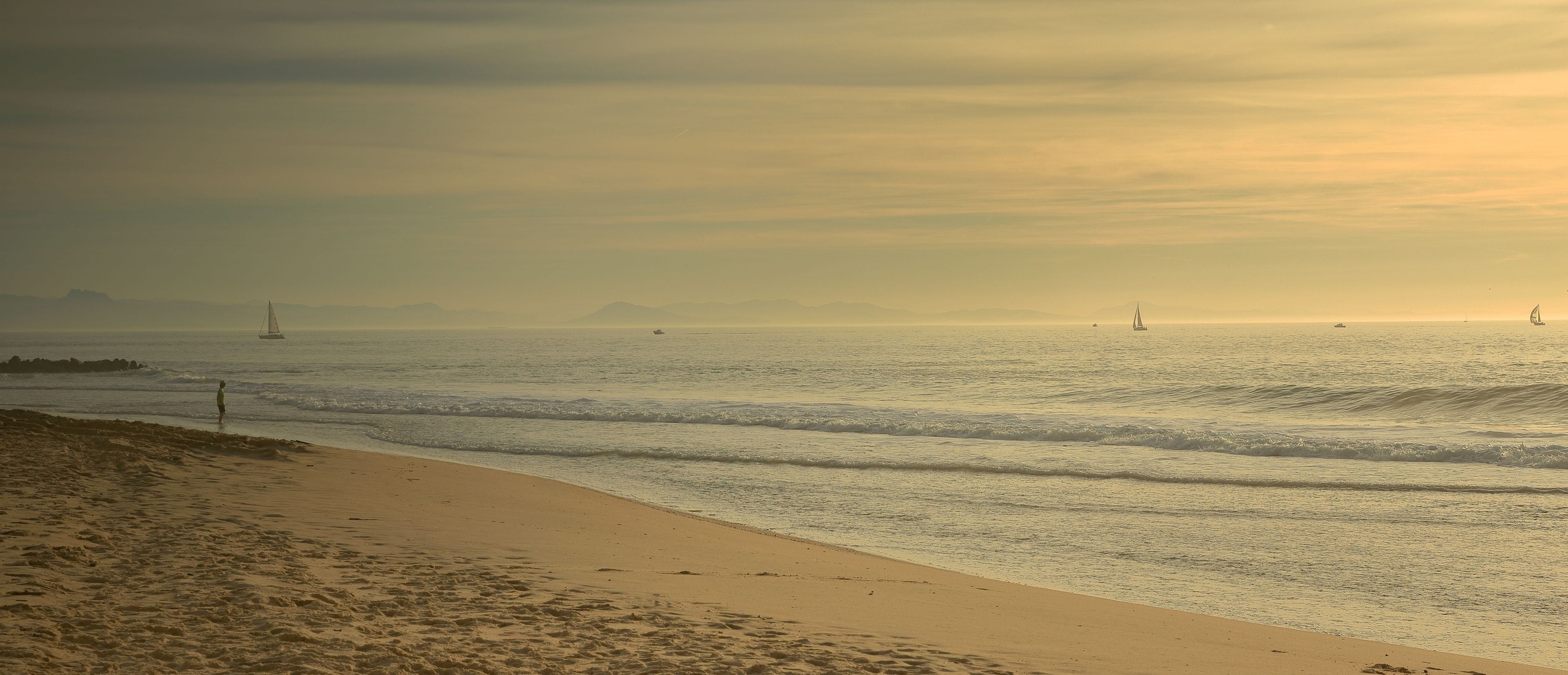 A beach with a sandy shore and gentle waves.