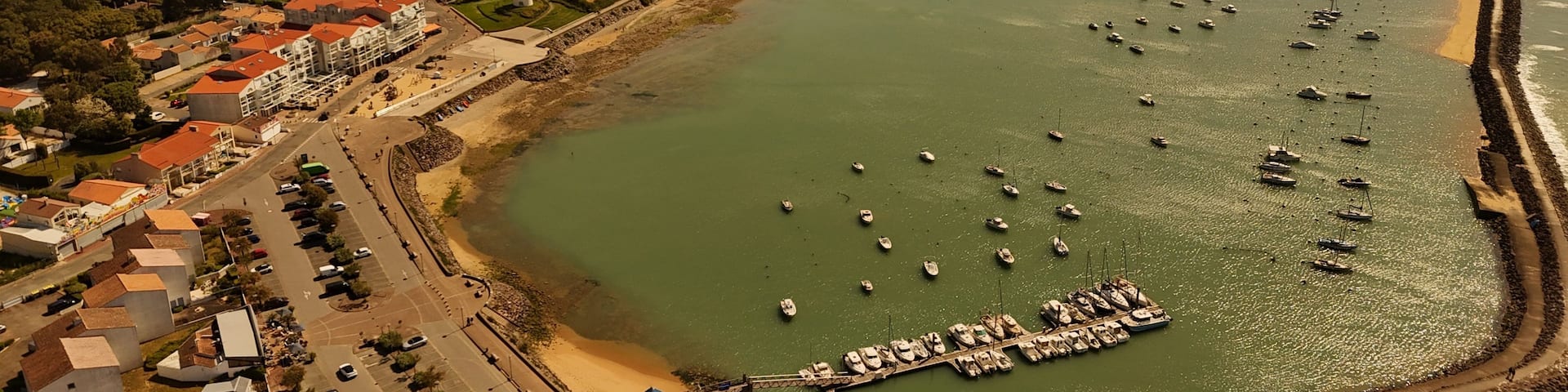 A coastal town with a marina, sandy beach, and residential buildings.