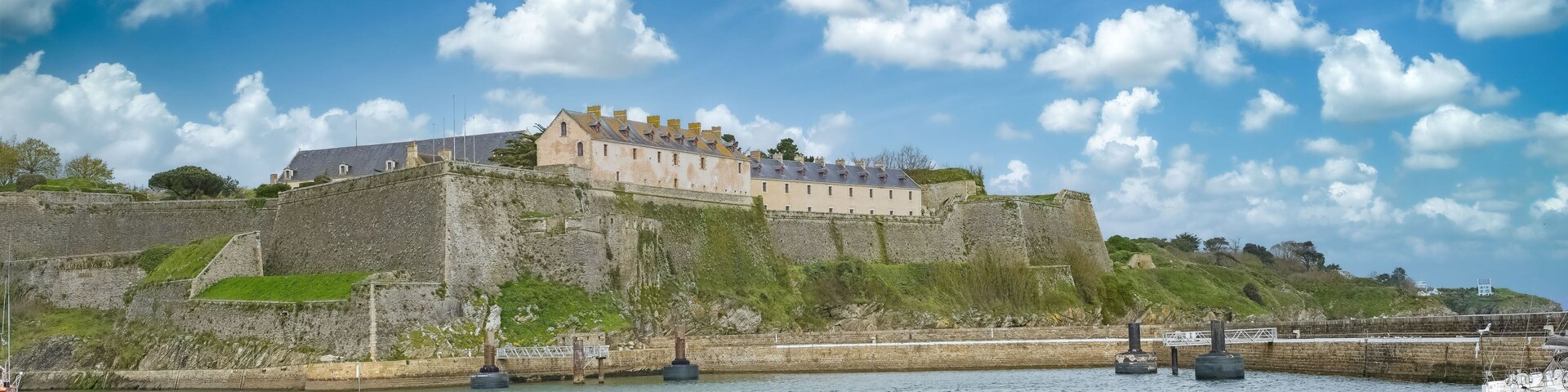 Un castillo histórico en una colina con vistas a un puerto lleno de barcos.