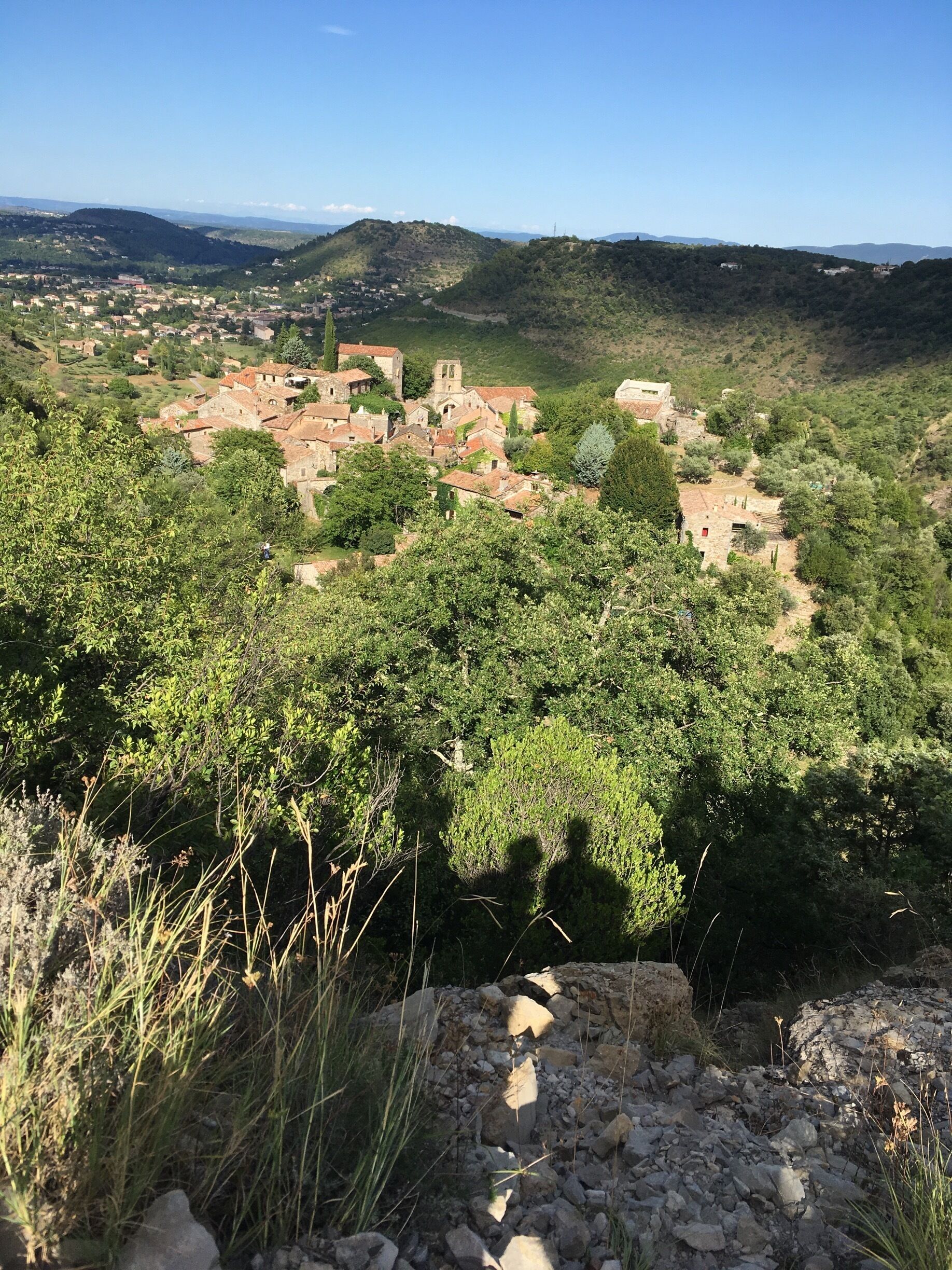 A village nestled in a valley with terraced fields, surrounded by hills and dense vegetation.