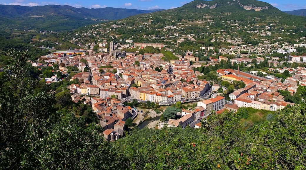 A town nestled in a valley with a river running through it, surrounded by green hills and mountains.