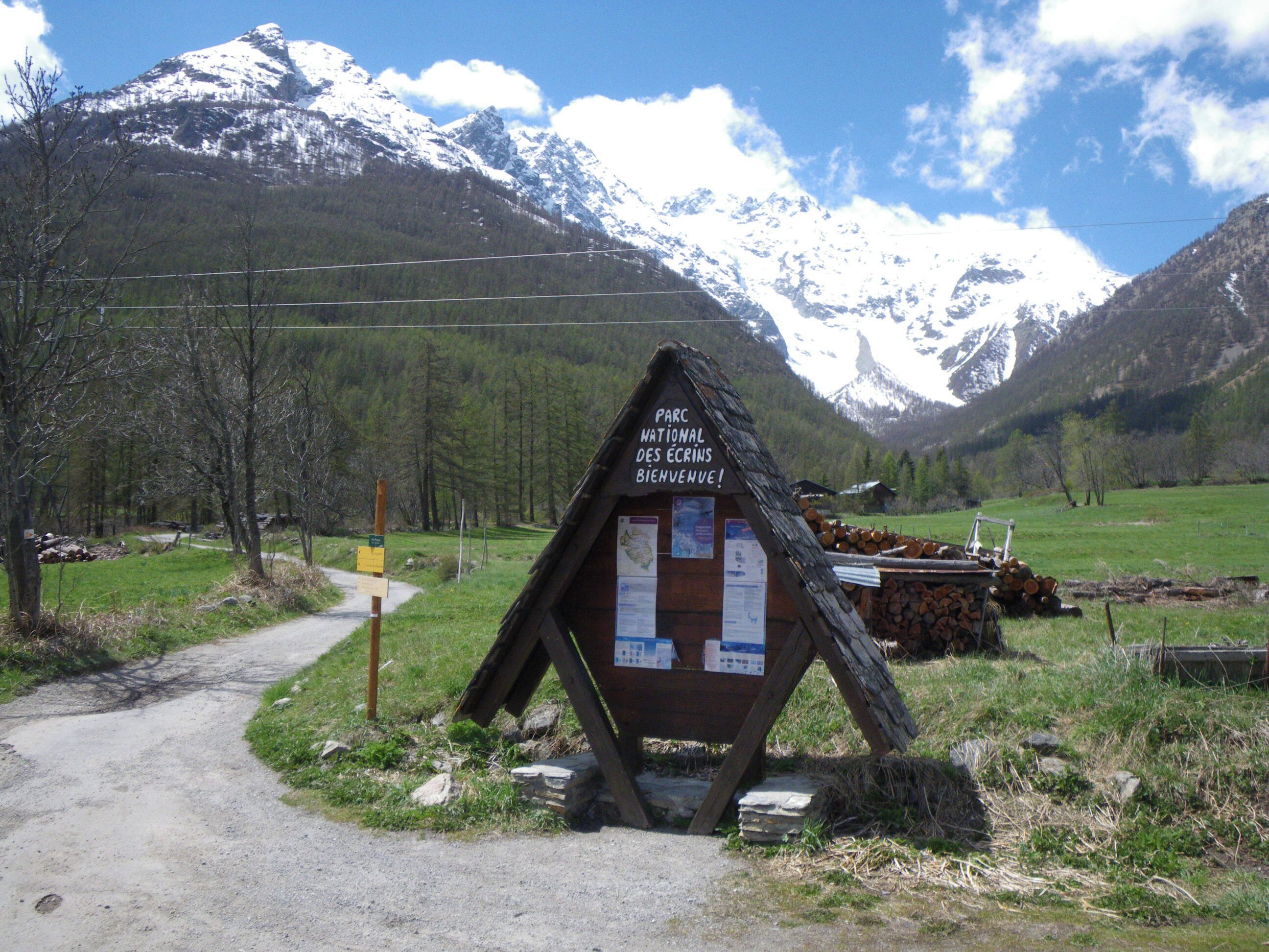 A wooden signpost with a welcome message for Parc National des Ecrins.
