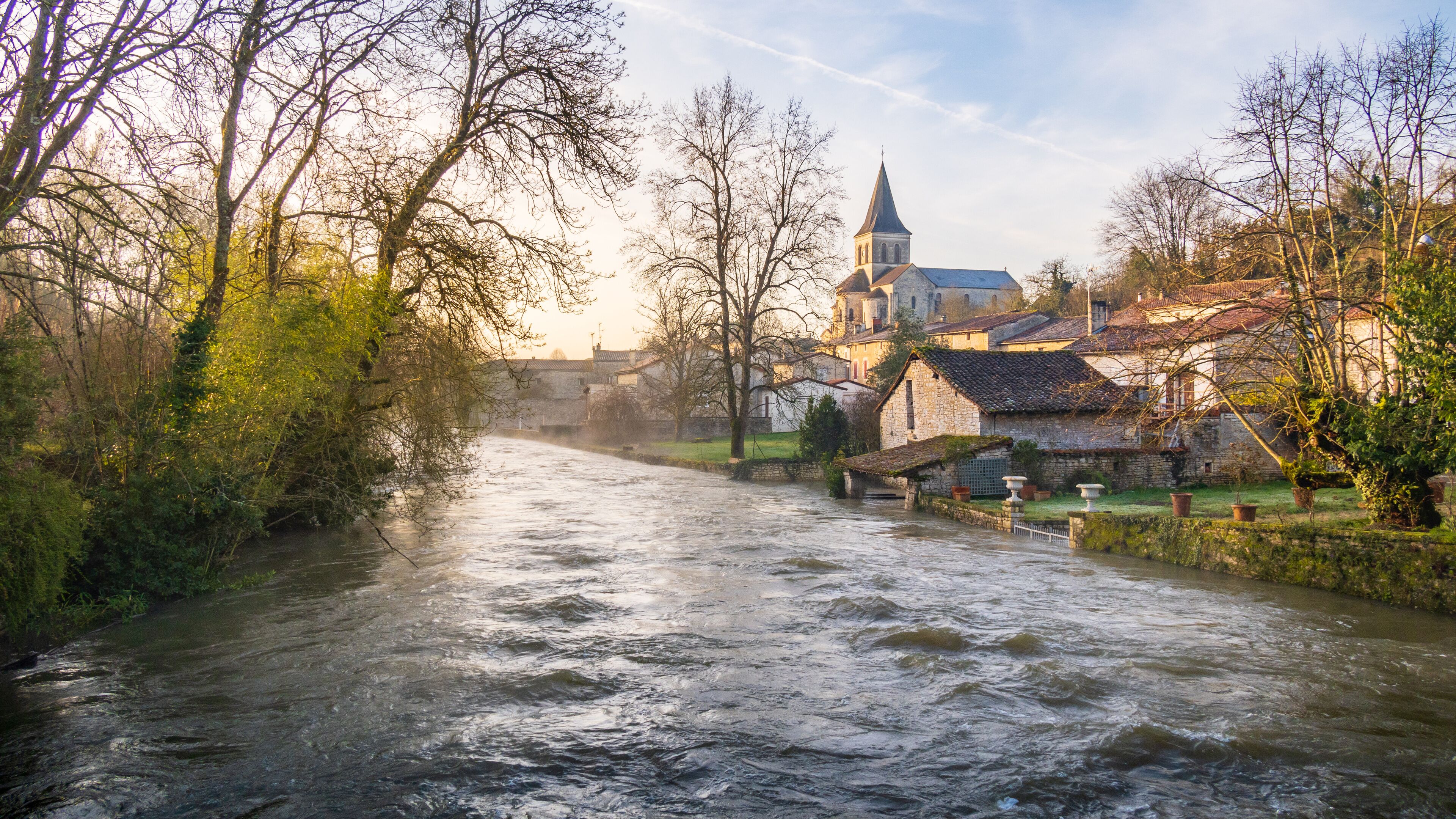 A river flowing through a town with historic buildings and a church.