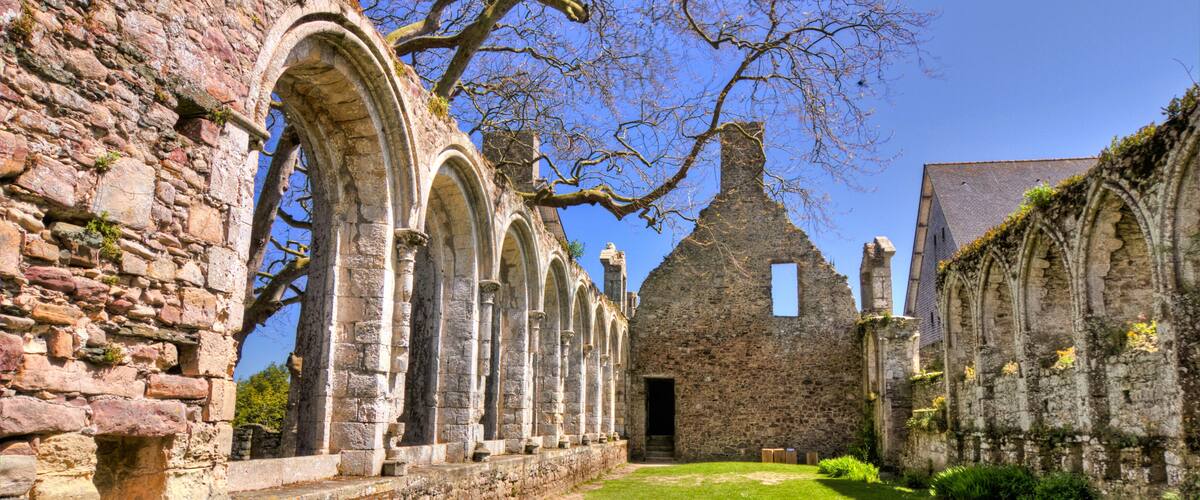 An ancient stone building with arched windows and a grassy courtyard.