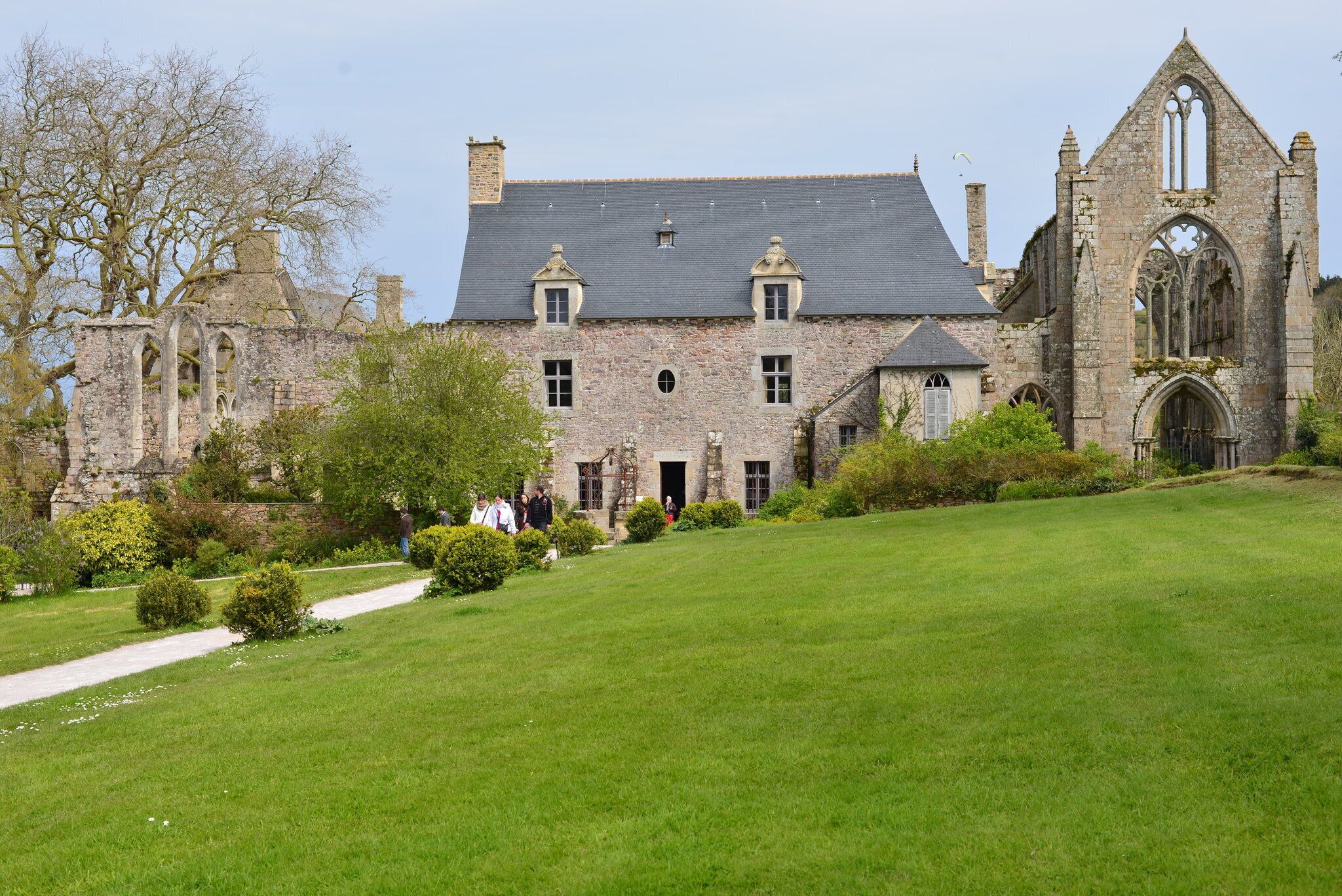 A historic stone building with a large lawn and a church with Gothic architecture.