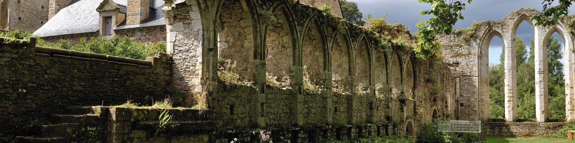 Un antiguo edificio de piedra con ventanas de arco y un patio cubierto de césped.