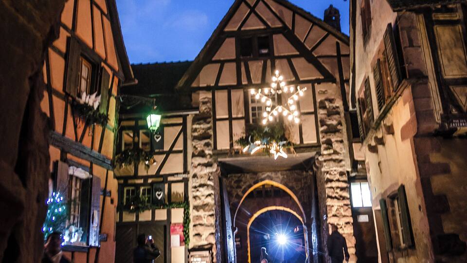 A cobblestone street with historic buildings and a large archway.
