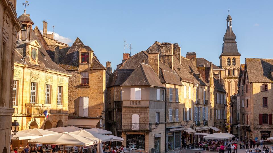 A bustling European market square with historic buildings and a prominent church tower.