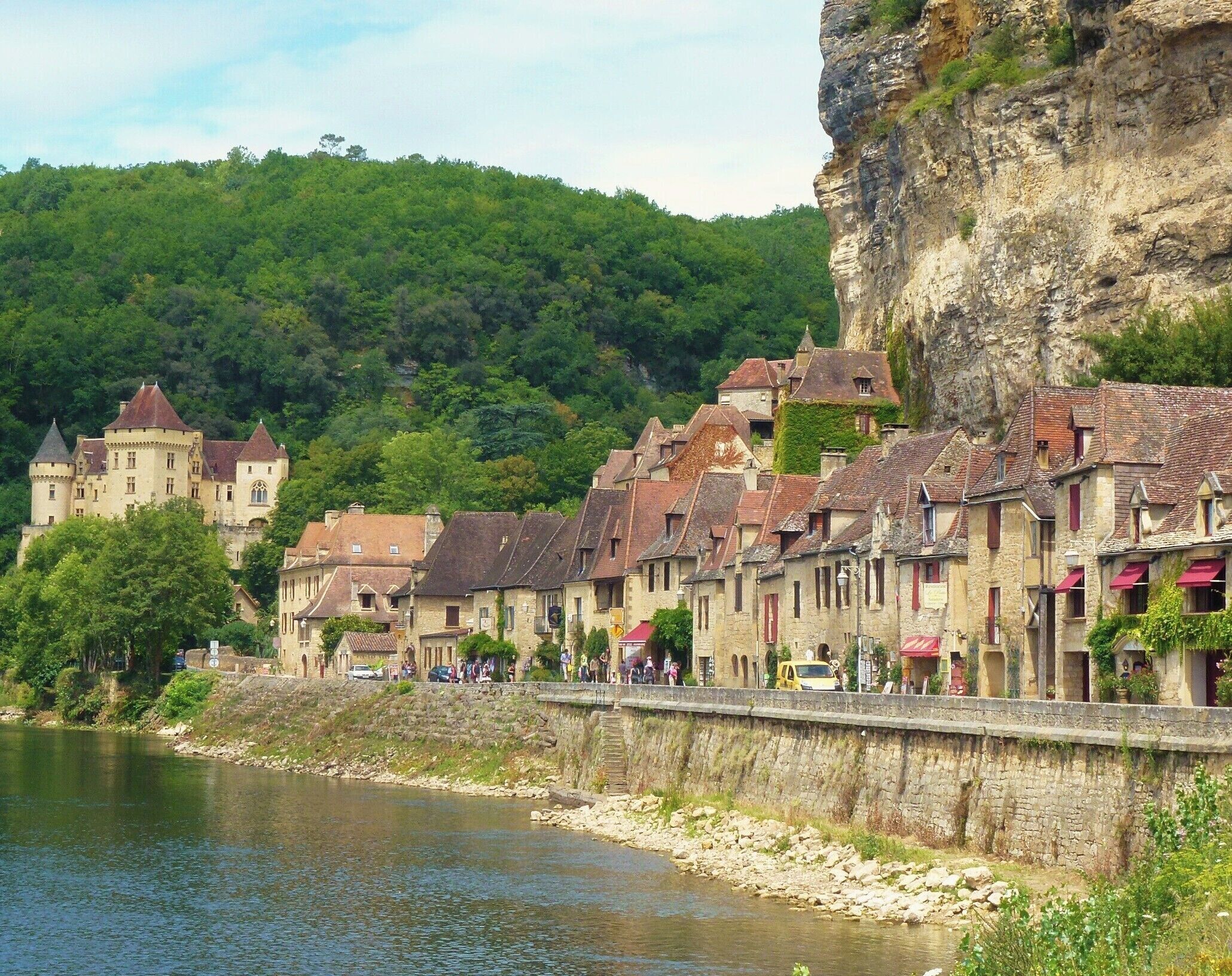 Eine Stadt an einem Fluss mit historischen Gebäuden, einer Burg und einer steilen Klippe.