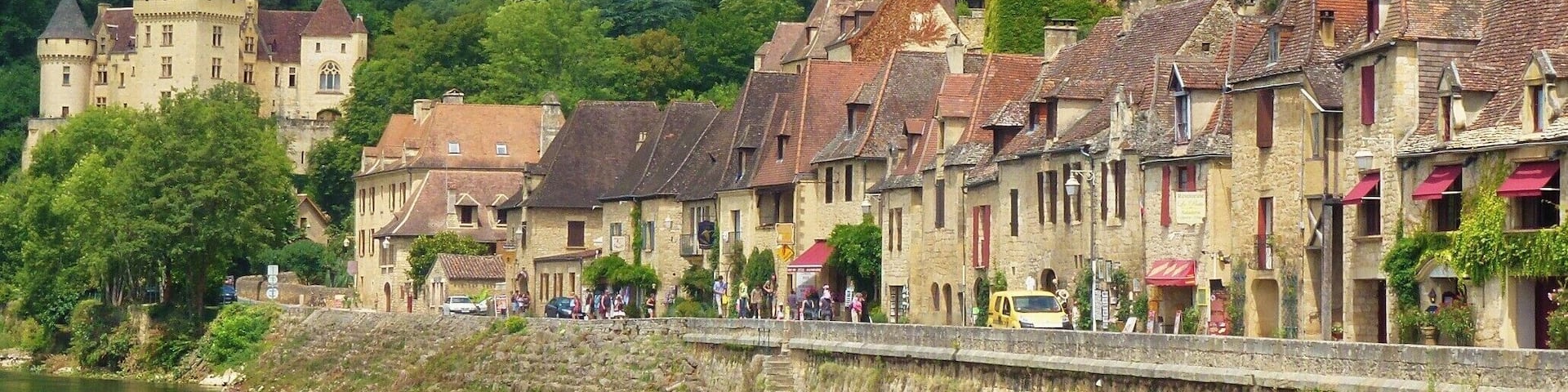 A riverside town with historic buildings, a castle, and a steep cliff.