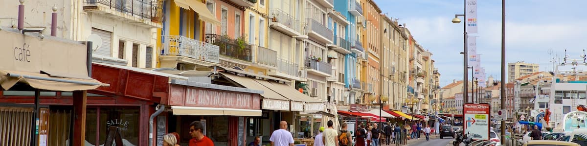 A bustling street with colorful buildings, outdoor cafes, and pedestrians.