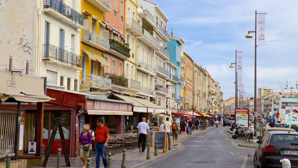 A bustling street with colorful buildings, outdoor cafes, and pedestrians.