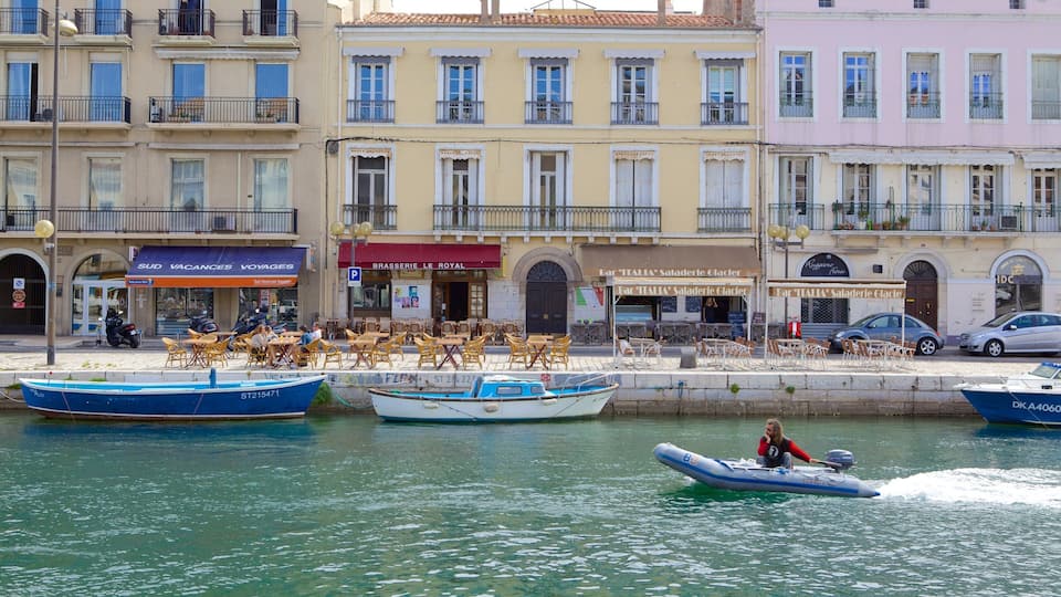 A waterfront with boats, a café, and buildings with shops.