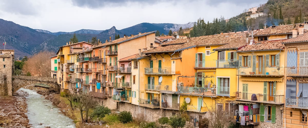 A river flowing through a town with colorful buildings and a stone bridge.