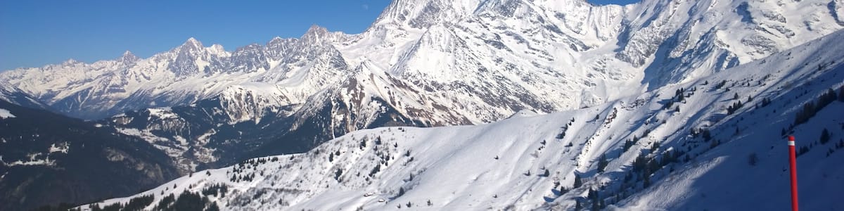 Une chaîne de montagnes enneigée sous un ciel bleu clair.