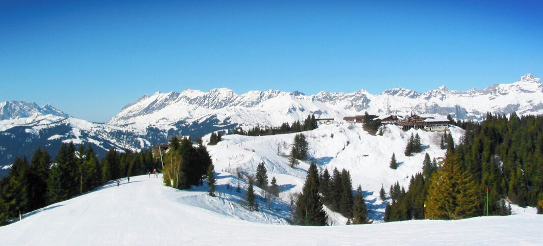 A snow-covered mountain landscape with a ski resort and a clear blue sky.