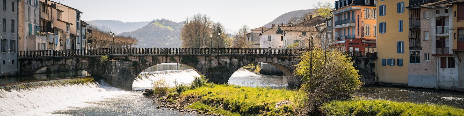 Un puente de piedra sobre un río, rodeado de edificios y colinas.