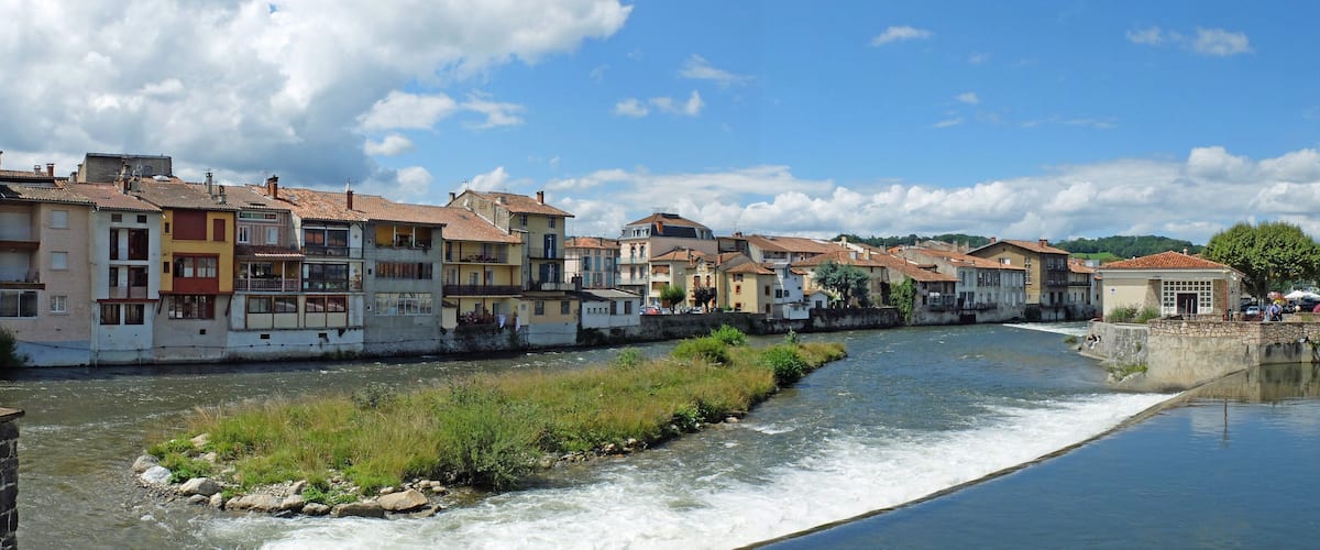 A river flowing through a town with colorful buildings and a stone bridge.