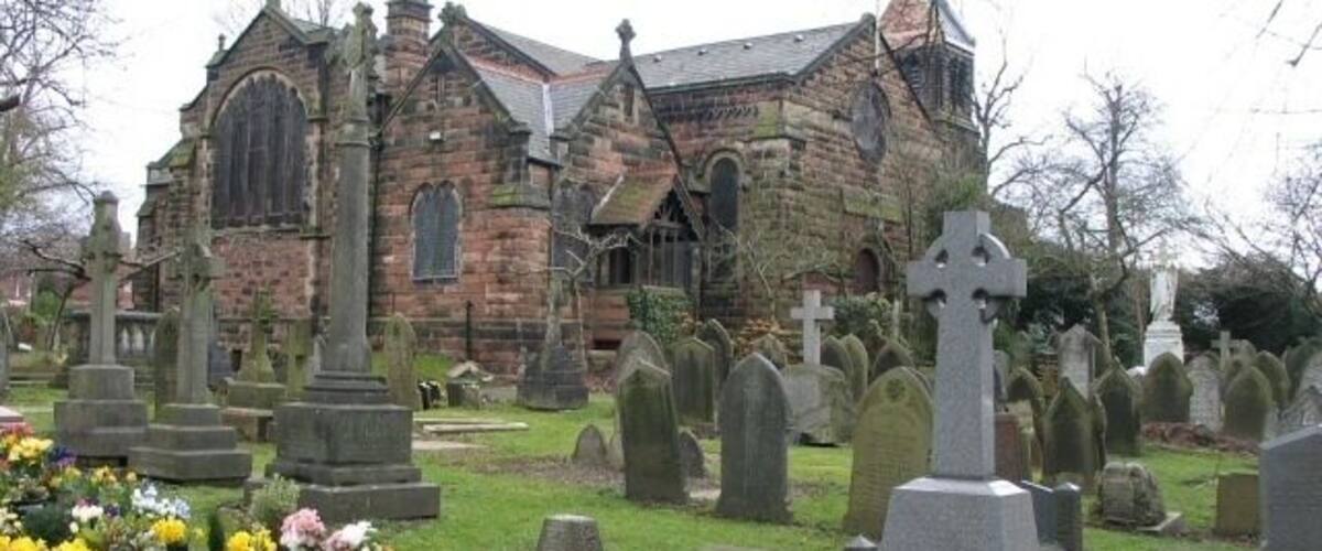 A church with a stone facade and a graveyard with numerous headstones.