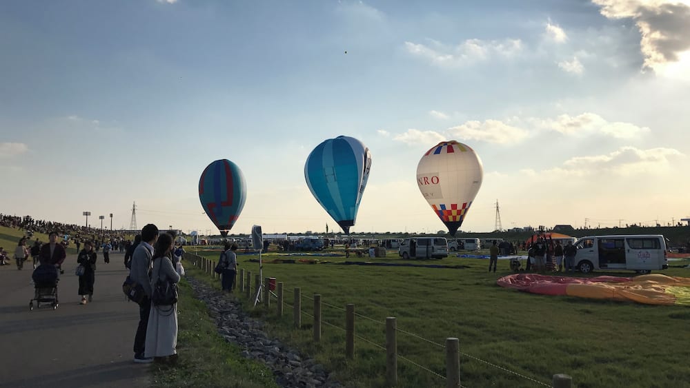 A hot air balloon festival with three balloons in the sky.