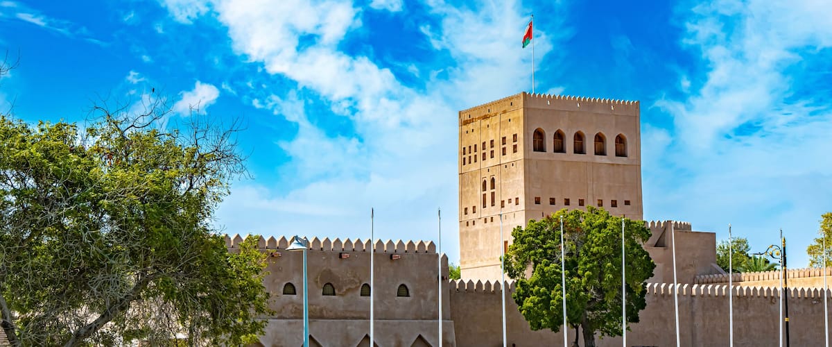 A historic fort with a prominent tower, surrounded by lush greenery and a clear blue sky.