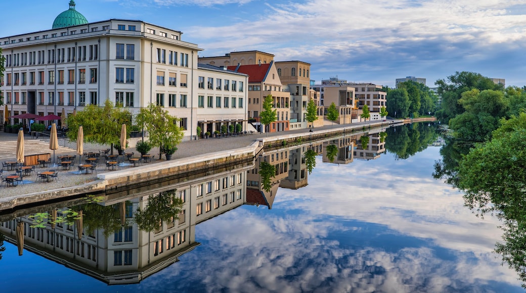 Un río que refleja edificios, una cúpula verde y un puente.
