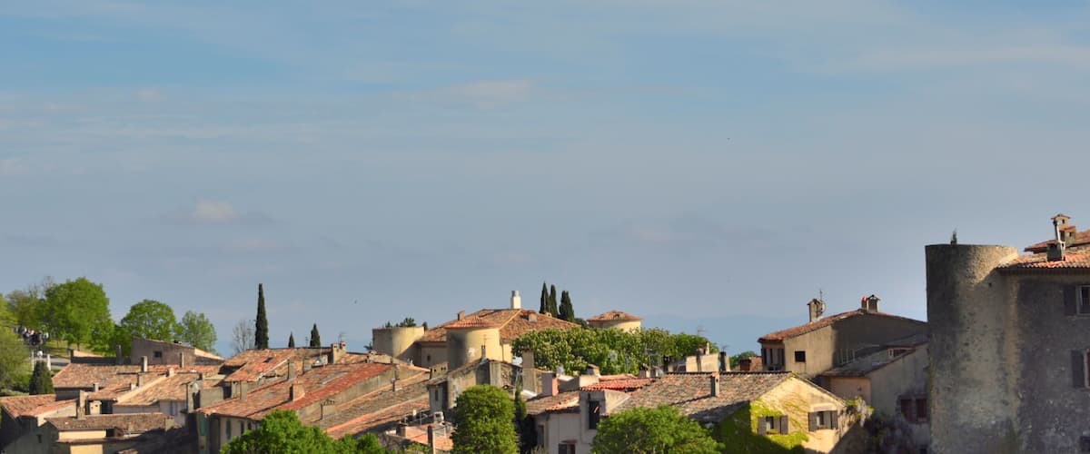 A historic town with terracotta-roofed buildings, a prominent church, and lush greenery.