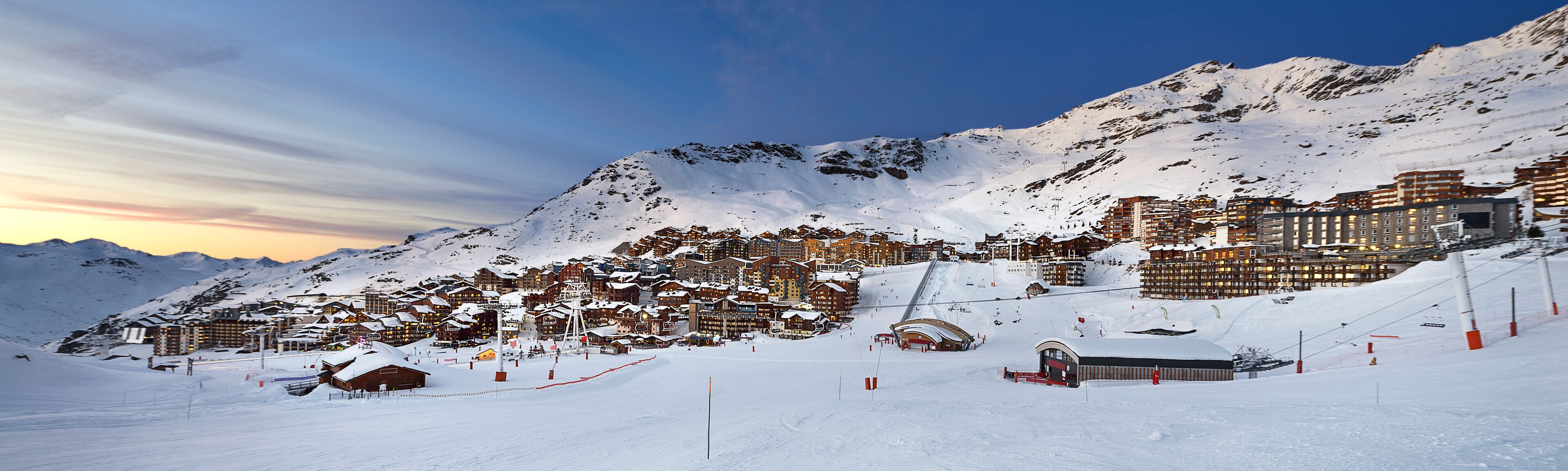 A snow-covered mountain town with ski slopes and buildings.