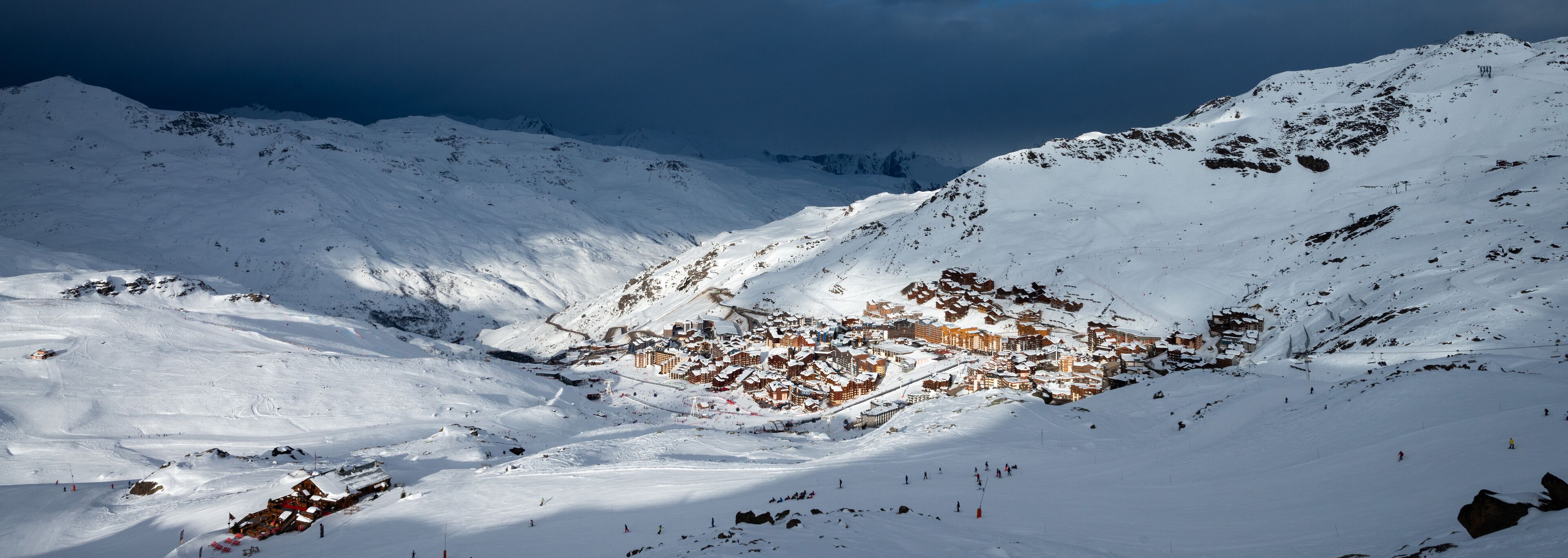 A snow-covered mountain with a ski resort and buildings.