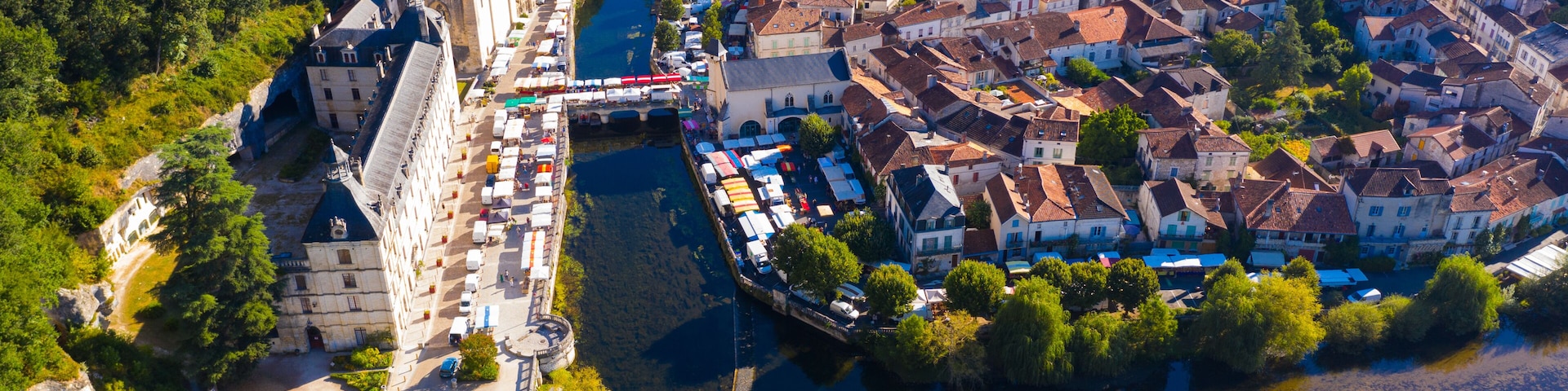 Vista aérea de un pueblo histórico con un río, un castillo destacado y un puente.