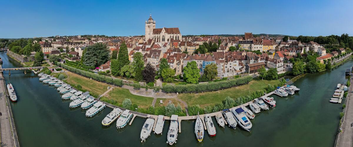 A riverside town with historic buildings, a prominent church, and a marina with boats.