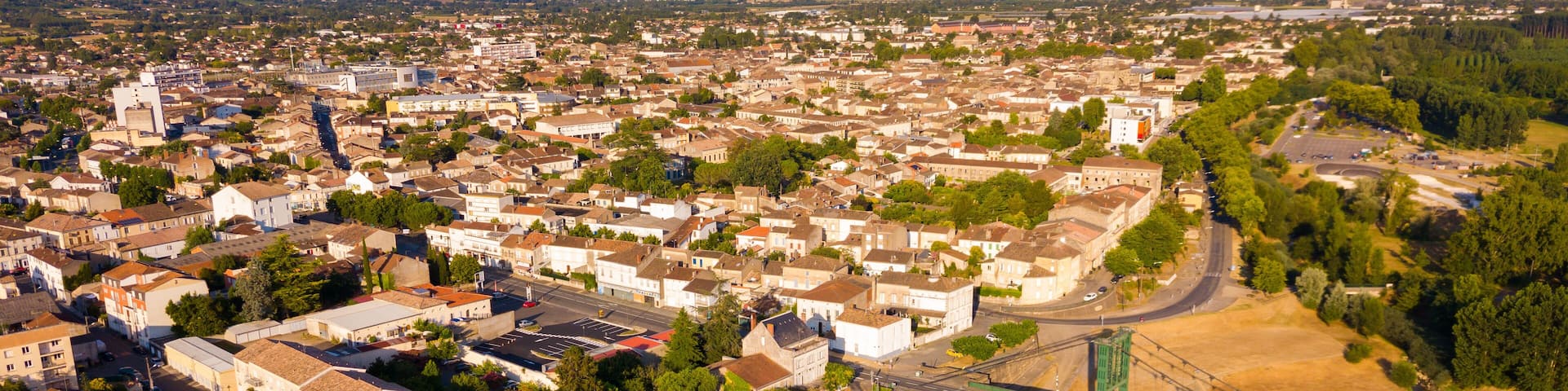 View from drone of small French town of Marmande with suspension bridge over Garonne river on summer day