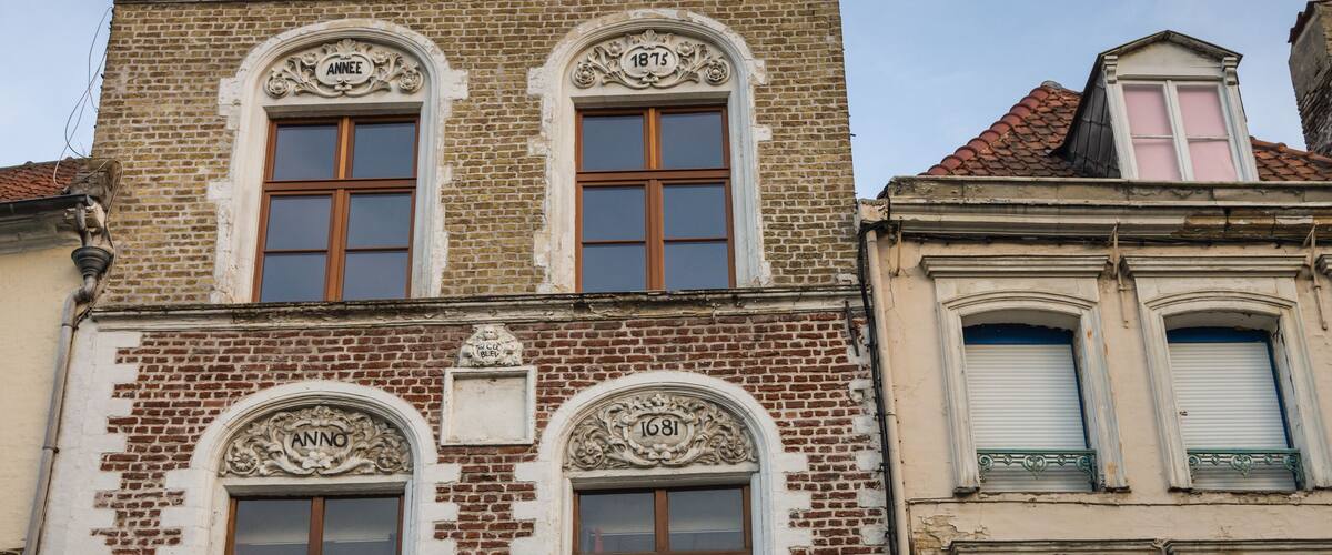A historic building with ornate window frames and decorative elements, including the year 1813 and 1681.